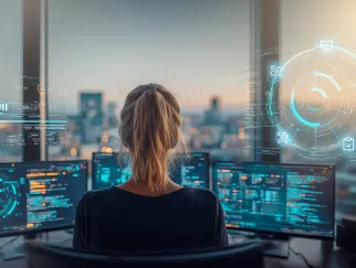 Eine Frau, die vor mehreren Computerbildschirmen sitzt